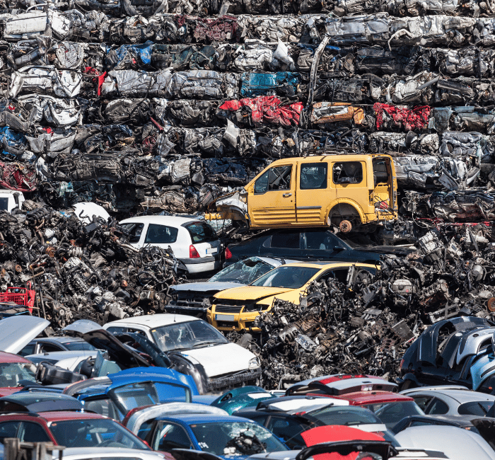 Schrottplatz mit gestapelten, verschrotteten Autos – Fachgerechte Auto Verwertung und Recycling von Altautos.